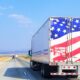 A Semi truck with the American Flag on the rear doors