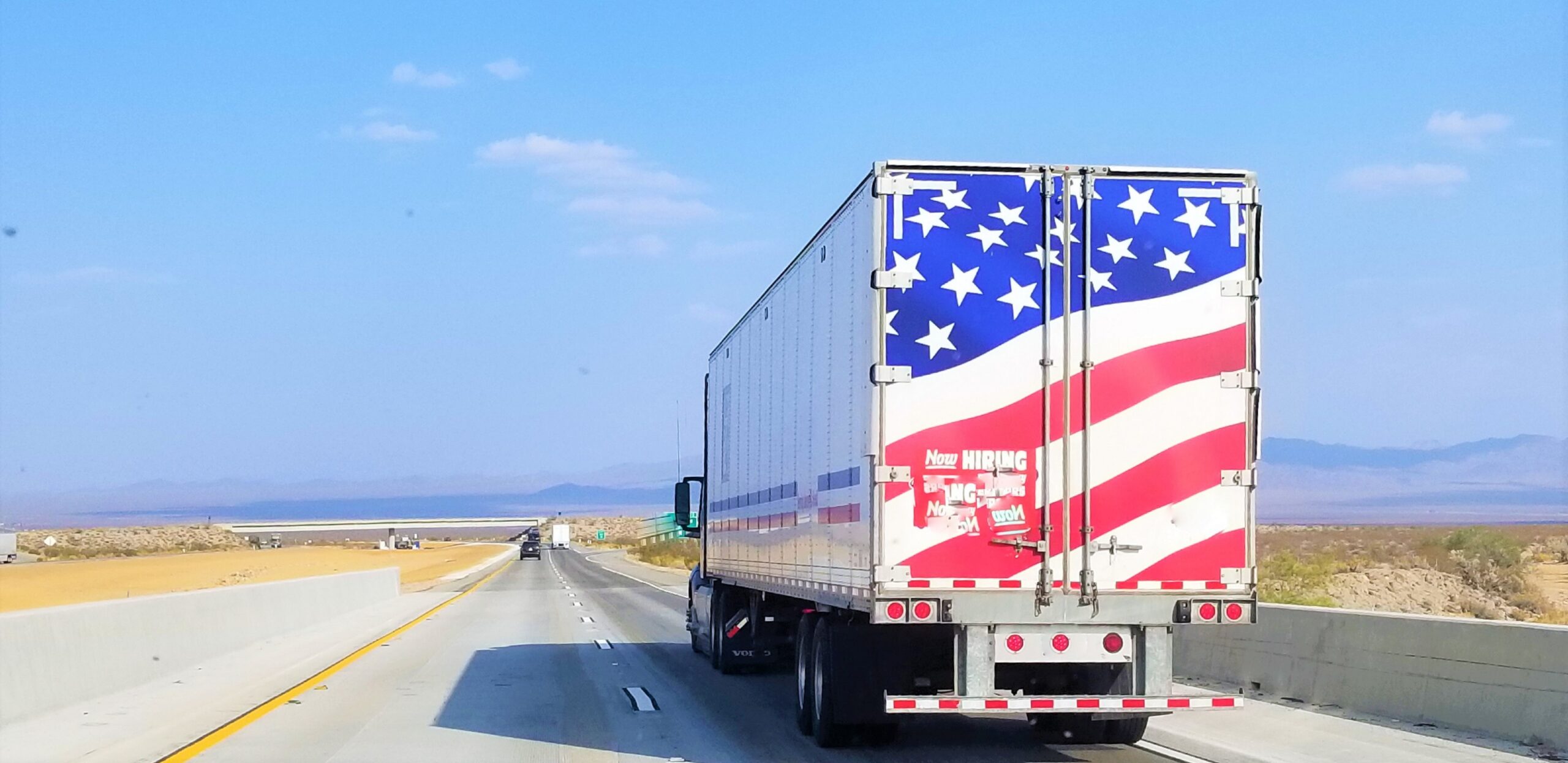 A Semi truck with the American Flag on the rear doors